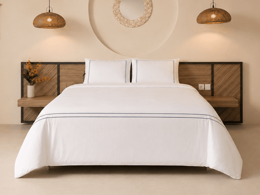A made bed with crisp white bedding and two white pillows, set against a modern wooden headboard in a minimalist bedroom.