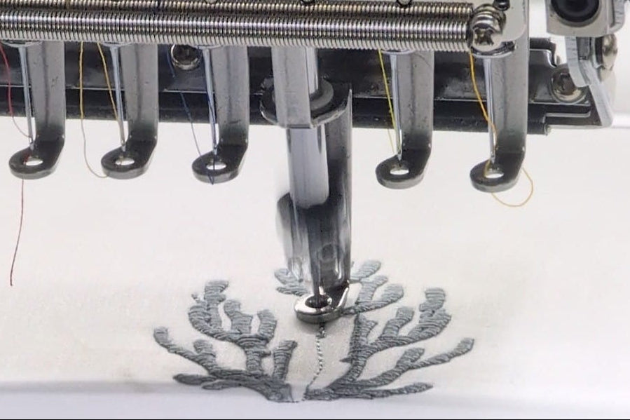 Embroidery machine needle stitching a design on fabric