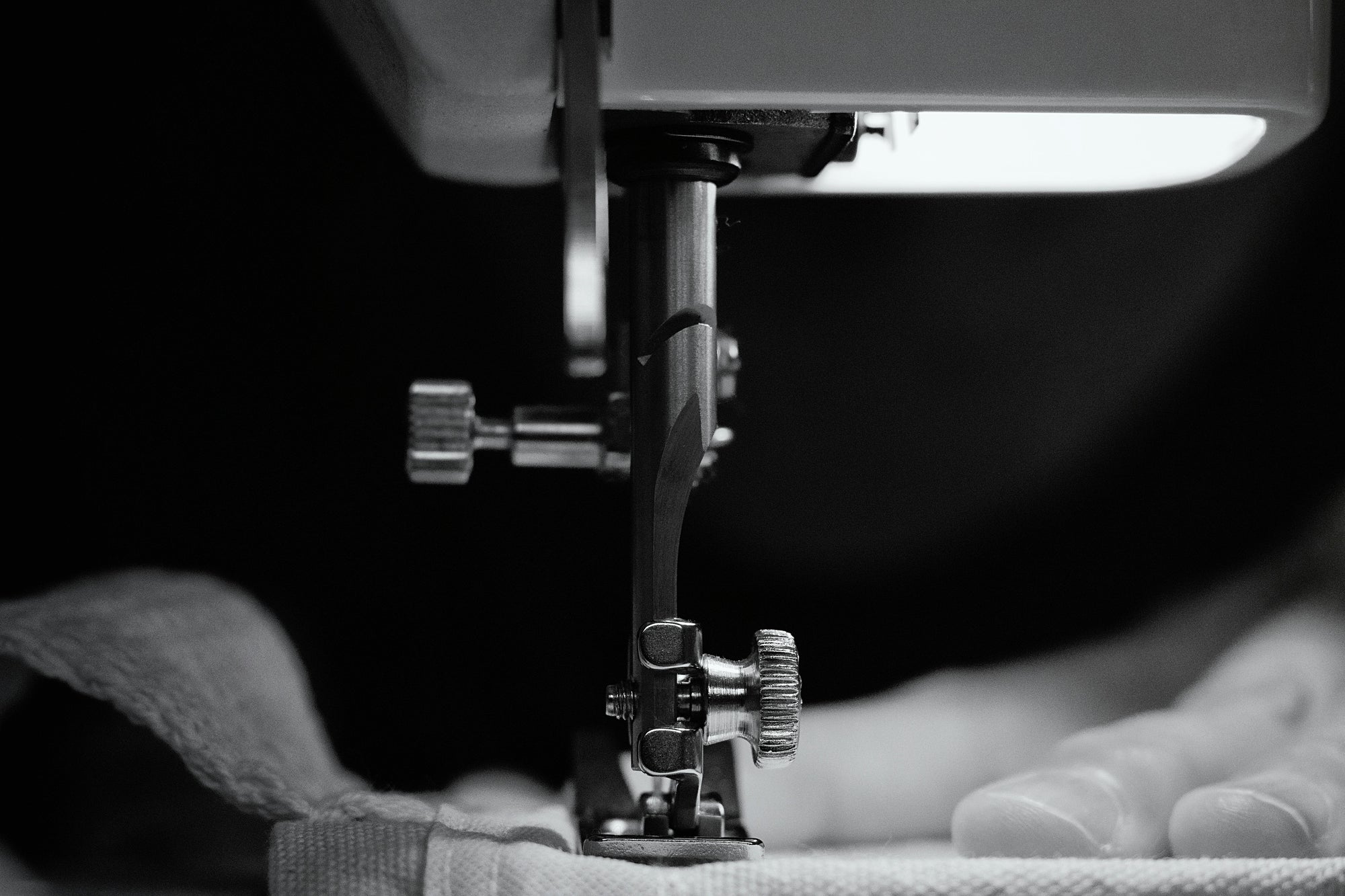 Close-up of a sewing machine needle in action with fabric underneath.