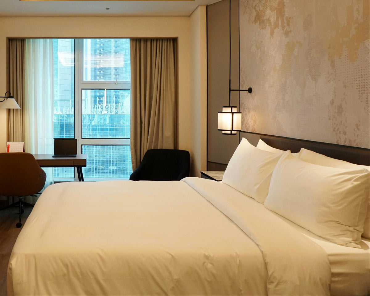 Neatly made bed in a well-lit bedroom with city view